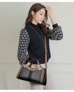 Elegante borsa a tracolla in pelle nera con manici marroni presentata da una modella