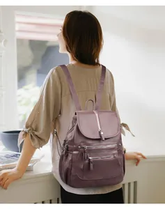 Vue de dos d'une femme portant un sac à dos vintage en cuir souple violet avec fermetures