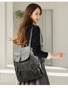 Mannequin portant un sac à dos vintage en cuir souple gris avec plusieurs fermetures.