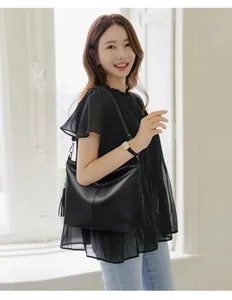 Elegant black pebble leather shoulder bag with tassel detail on Asian model