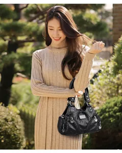 Elegantes asiatisches Model mit einer schwarzen Vintage-Handtasche aus weichem Leder.