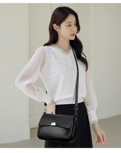 Black leather crossbody shoulder bag with crocodile print texture flap on model