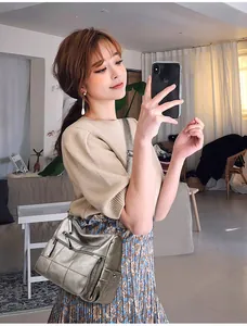Modelo luciendo un bolso bandolera de cuero suave plateado con varios bolsillos
