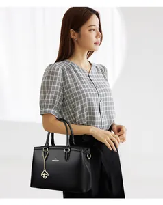 Elegante schwarze Lederhandtasche, von einem Model gehalten, zeigt modischen Stil.