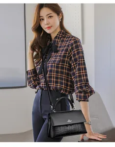 Detail view of an Asian model styling a chic black leather crossbody bag with a kangaroo logo.