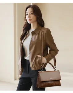 Close-up detail of elegant brown leather handbag featuring embossed patterns on model