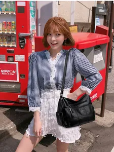 Modelo con bolso bandolera de piel suave negra con múltiples bolsillos en un entorno urbano