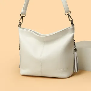 Elegant white pebbled leather bucket bag featuring tassel accents and adjustable shoulder strap