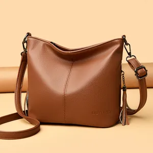 Elegant brown faux leather crossbody bucket bag with tassel detail and embossed logo