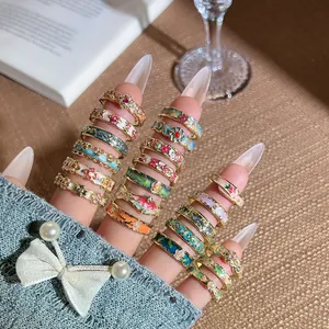 Makroansicht mehrerer farbenfroher Vintage-Emaille-Blumenringe mit Kristallakzenten