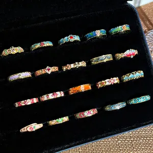 Verschiedene bunte Vintage-Emaille-Ringe mit Blumenmuster in einer schwarzen Samtbox.