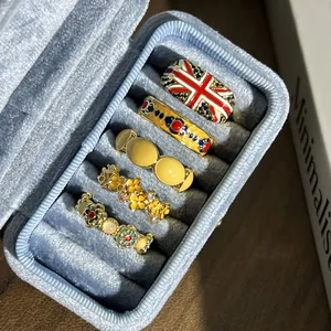 Detail van vintage emaille ringen met Union Jack en bloemen in een sieradendoos.