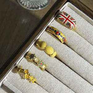 Detail van vintage emaille ringen met Union Jack en bloemmotieven in een juwelendoosje.