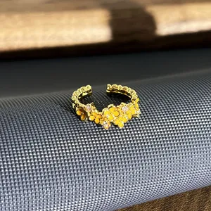 Detail van een goudkleurige emaille bloemenring met fonkelende kristallen accenten.