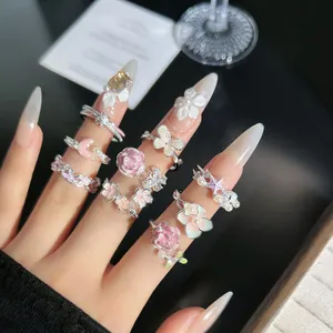 Detalle de cerca de anillos ajustables románticos con flores rosas y mariposas