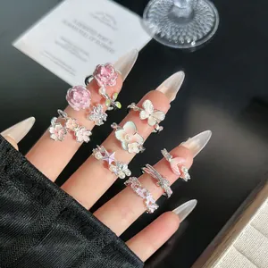 Detalle de anillos ajustables románticos con flores rosas mariposas y perlas