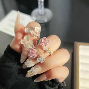 Detalle macro de delicados anillos de flores esmaltadas en rosa y blanco con perlas