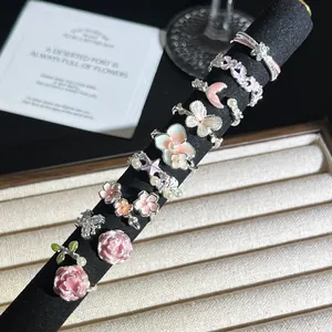 Vista detallada de varios anillos de esmalte rosa con flores y mariposas en soporte