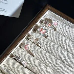 Vista detallada de anillos abiertos de flores rosas y mariposas en un joyero elegante