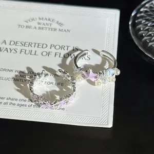 Vista detallada de elegantes anillos abiertos de plata con flores rosas y perlas.