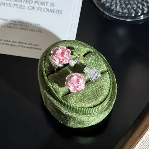Detalle macro de anillos de flores de esmalte rosa en una caja de terciopelo verde.