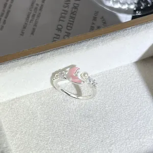 Detalle macro de un delicado anillo de plata con pétalo de flor rosa y perlas.