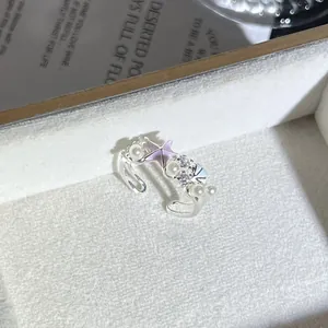 Primer plano de anillo con flor rosa, perlas y cristales en un joyero elegante.