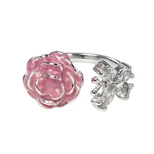 Vista detallada de un anillo abierto con una rosa rosa y una mariposa con cristales.