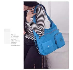 Modell mit großer blauer Oxford-Stoff Umhängetasche mit vielen Taschen.