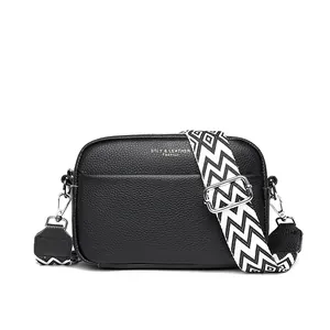 Black leather crossbody bag with a wide geometric patterned shoulder strap.