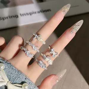 Detailaufnahme eleganter Perlen- und Kristall-Schleifenringe an gepflegten Fingern