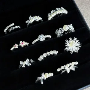 Detailed view of assorted silver rings with pearls and butterflies in a display tray.