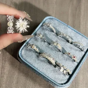 Detailed view of silver vintage pearl and bow rings arranged in a blue velvet jewelry box