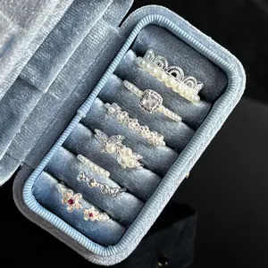 Detailed macro view of retro pearl ring set with bow and flower motifs in a blue box.
