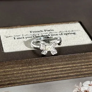 Detailansicht eines eleganten silbernen Schleifenrings mit Perle und Kristallen.