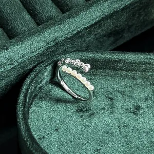 Elegant close-up of a vintage pearl bow ring on luxury green velvet background