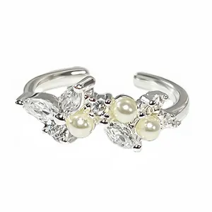 Eleganter silberfarbener Schmetterlingsring mit weißen Perlen und glitzernden Zirkoniasteinen.