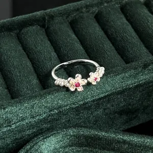 Macro detail of a vintage silver-tone open ring featuring pearls and red flower stones