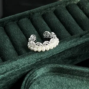 Detailed close-up of a vintage French style lace pearl ring on a dark green velvet display