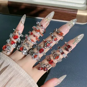 Detailed view of multiple pomegranate red floral and butterfly rings on a model's hand