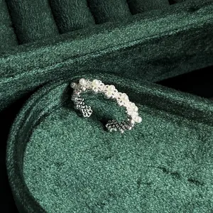 Macro detail of French vintage silver lace ring with white pearls on green velvet