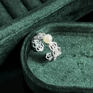 Exquisite close-up of a vintage lace silver ring with a pearl on green velvet