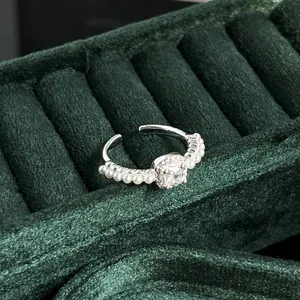 Elegant French vintage pearl ring with sparkling central stone on green velvet background