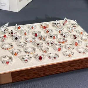 Close-up detail of various pomegranate red floral open rings on a velvet display tray