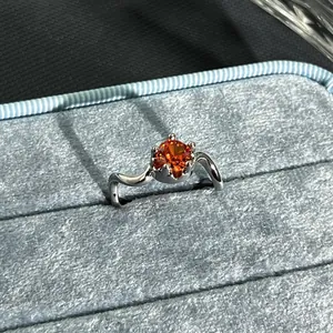 Close-up of pomegranate red gemstone ring with wavy silver band in velvet box.