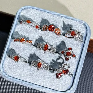 Macro view of pomegranate red floral open rings set displayed in a blue velvet box