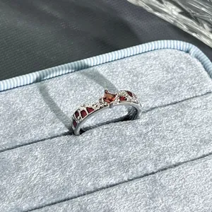 Close-up macro view of a garnet red adjustable ring with floral accents in a blue box