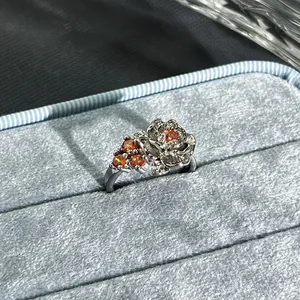 Macro view of a silver flower ring with pomegranate red stones in a velvet box