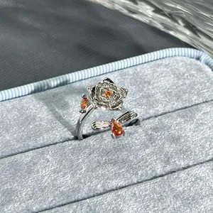Close-up of elegant silver flower and bee open ring with vibrant orange stones