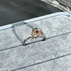 Detailed macro view of a silver flower-shaped open ring with red garnet center stone.